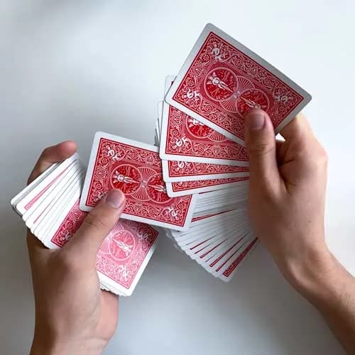 Das Deck wird zwischen beiden Händen aufgefächert, eine Karte steht seitlich hervor