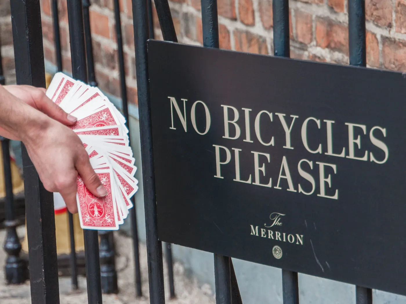 Meine Hand mit aufgefächertem Bicycle-Deck vor einem Schild „No bicycles please“ in Dublin